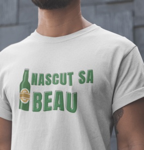 Tricou alb cu mesajul 'Născut să Beau', scris cu litere verzi, alături de o imagine stilizată a unei sticle de bere. Tricoul este purtat de un bărbat cu barbă, iar fundalul este neutru, cu un perete de culoare gri.