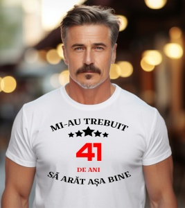 Un bărbat purtând un tricou alb cu mesajul: „Mi-au trebuit 41 de ani să arăt așa bine”
