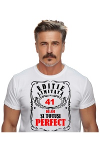 Un bărbat purtând un tricou alb cu mesajul: „Ediție limitată, 41 de ani și totuși perfect”. Bărbatul afișează o atitudine veselă și pozitivă.