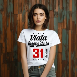 O femeie purtând un tricou alb cu textul  'Viața începe de la 31 de ani'. Fundal din lemn cu diferite nuanțe de maro și verde.