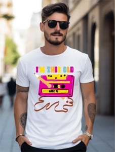 Bărbat purtând tricou alb cu textul 'I'm this old' și imaginea unei casete audio roz cu un creion și o bandă magnetică desfășurată, reprezentând nostalgia pentru era casetelor audio