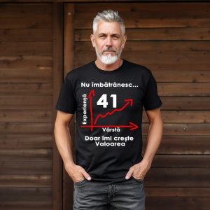 Un bărbat cu păr grizonat și barbă, purtând un tricou negru cu mesajul: „Nu îmbătrânesc... Doar îmi crește valoarea” și un grafic care indică vârsta de 41 de ani pe axa vârstei și experienței. Bărbatul se află într-un cadru exterior, lângă un perete din l