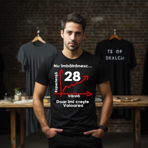 Un tânăr purtând un tricou negru cu mesajul: „Nu îmbătrânesc... Doar îmi crește valoarea” și un grafic care indică vârsta de 28 de ani pe axa vârstei și experienței. În fundal se află alte tricouri expuse într-o încăpere.