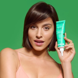Un model (doamna foarte draguta) zambind tine in mana produsul Peeling Scalp Eveline - Curățare Profundă & Creștere Vizibilă a Părului
