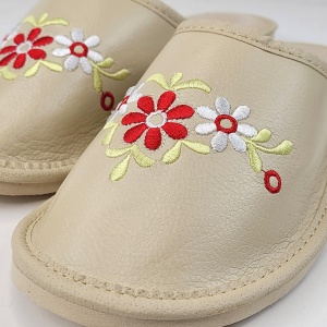 Detaliu al broderiei florale elegante realizată pe pielea naturală crem.