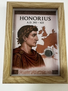 Tablou elegant, dimensiuni 14.8 x 19.8 cm, ce conține o monedă autentică din timpul împăratului roman HONORIUS ( 393-423 ) , prezentată într-un design artistic inspirat din stilul roman antic.
