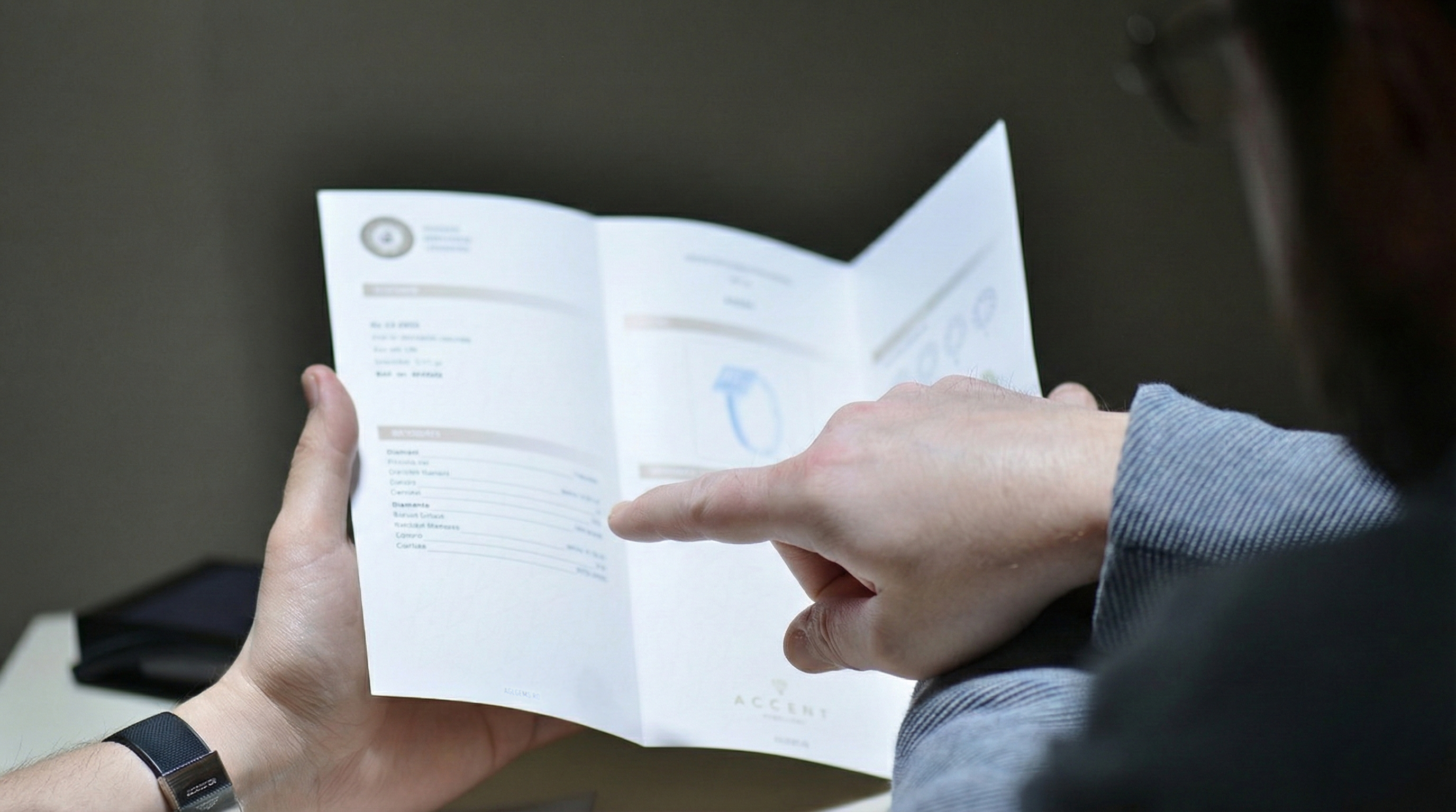 Gemolog explicand clientului specificațiile tehnice (carate, claritate, culoare) din certificatul gemologic, ca etapă finală a procesului de consiliere si evaluare bijuterii