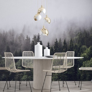 Fototapet pădure în ceață în zona de dining modern cu masă ovală albă, scaune din răchită și lămpi aurii suspendate